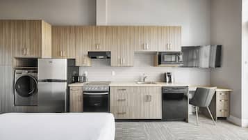 A modern kitchen with wooden cabinets, stainless steel appliances, a microwave, and a flat-screen TV.