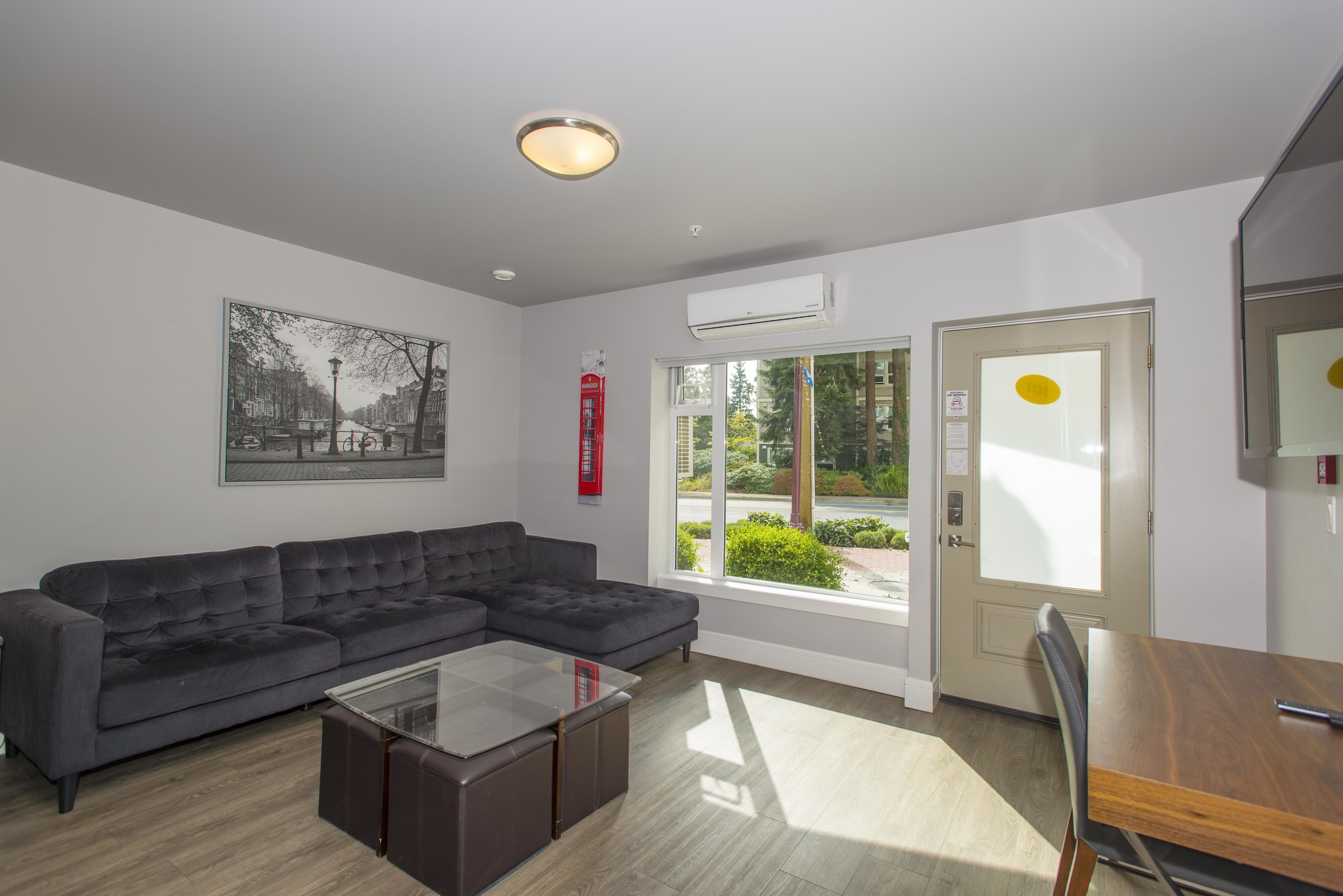 A modern living room with a sectional sofa, a glass coffee table, and a dining area with a wooden table and chairs.