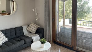 A modern living room with a grey sofa, a round mirror, and a white coffee table.