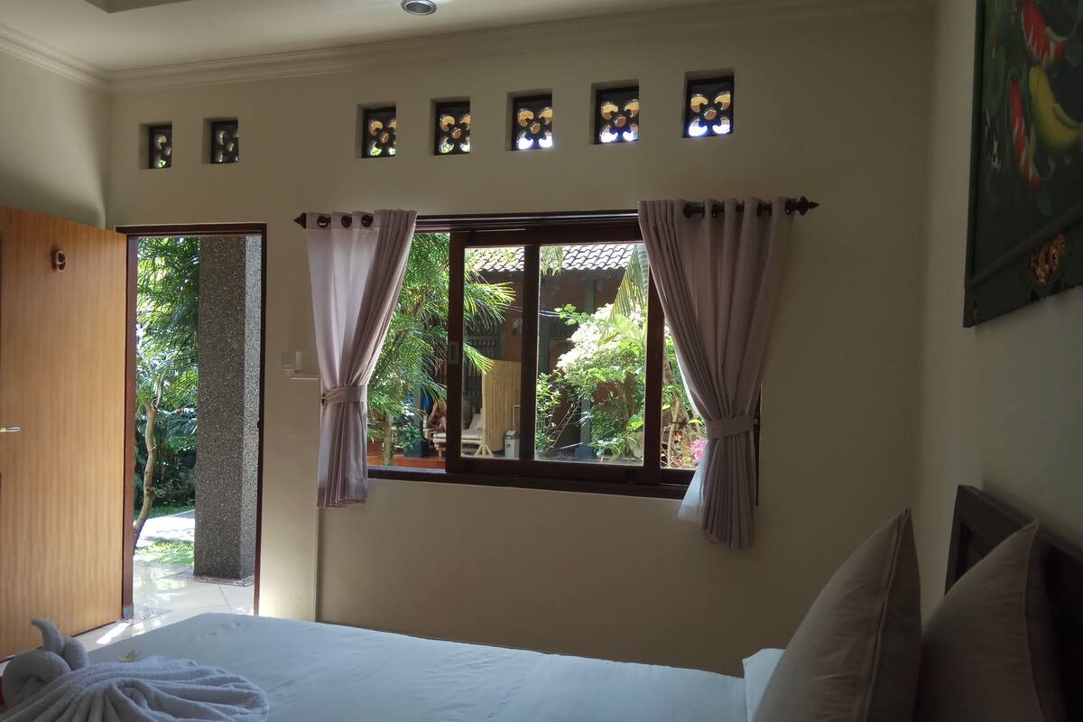 Une chambre à coucher avec un lit, des rideaux, une fenêtre et une porte.
