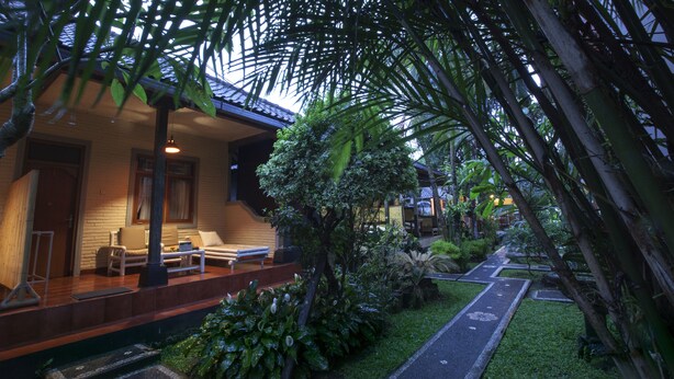 Ein Haus mit überdachter Veranda, einem Weg und üppiger Bepflanzung.
