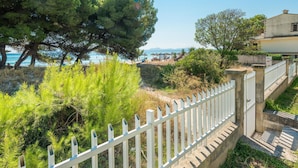 A coastal property with a white fence, trees, and a view of the sea.