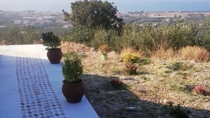 En terrasse med plantekrukker og udsigt over landskabet.