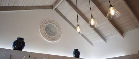 Una cocina con vigas de madera, lámparas colgantes y jarrones decorativos en la encimera.