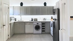 Una cocina moderna con armarios grises, lavadora, lavavajillas y refrigerador.
