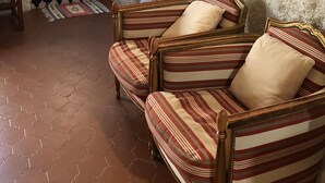 Ein gemütliches Wohnzimmer mit einem gemusterten Sofa, einem Holzstuhl, einem Teppich mit Muster und einer weißen Tür mit Fenster.