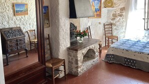 Ein rustikaler Raum mit Kamin aus Stein, Holzmöbeln und einem Bett mit gemustertem Überwurf.