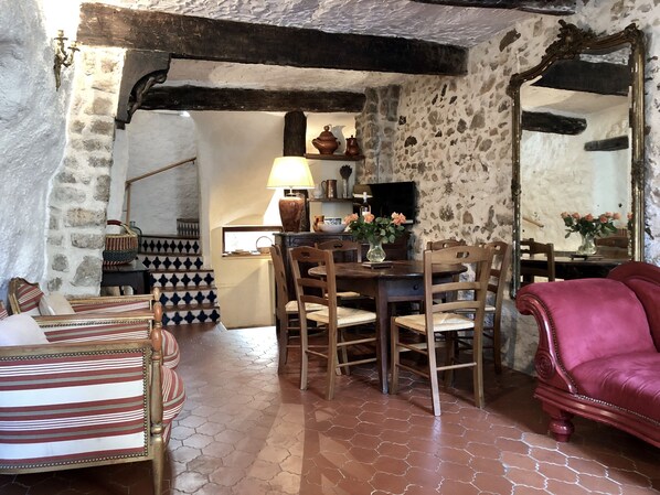 A rustic dining area with a wooden table, chairs, and a red sofa.