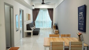 A modern living room with a sofa, a dining table, and a ceiling fan. - Comfy Home at Sutera Avenue (Kota Kinabalu)
