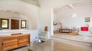 Un vaste espace de vie comprenant un meuble en bois, une table en verre et un canapé blanc.