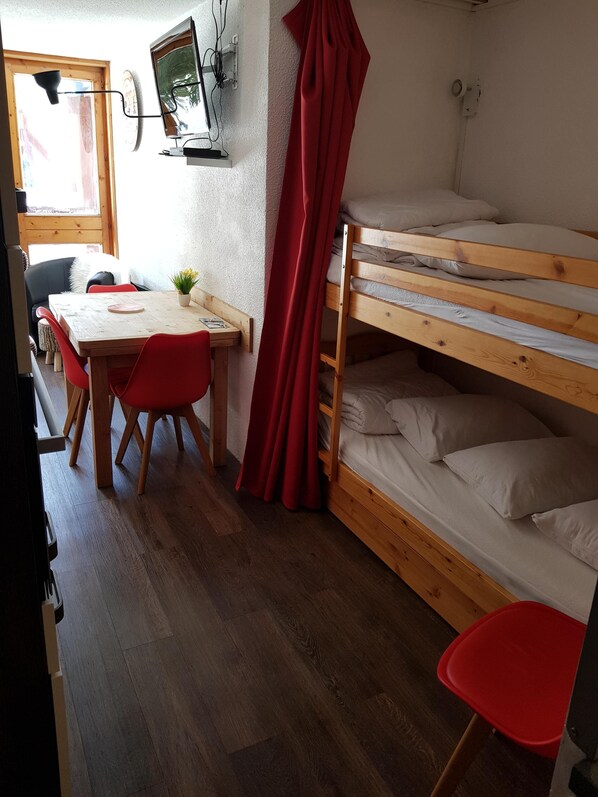 Una habitación con una cama nido, un escritorio de madera, una silla y una mesa.