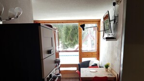 Eine kleine Küche mit Essbereich, Holzboden und Blick durch ein großes Fenster.