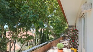 Un balcón con una mesa de madera, plantas en macetas y un muro ajardinado.