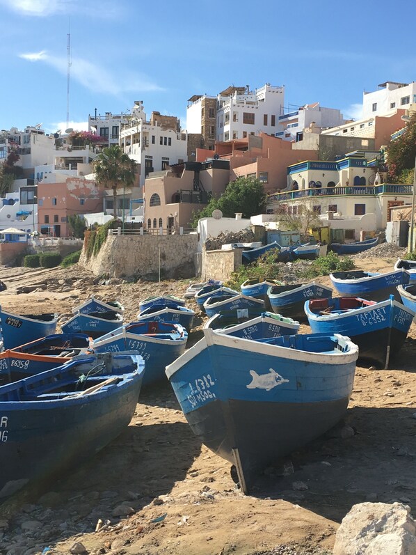 A coastal area with numerous boats docked on the shore, surrounded by buildings with balconies and terraces.