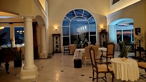 A spacious interior with high ceilings, a grand piano, and a large arched window. - Sunshine Mountain Bed and Breakfast (San Marcos)