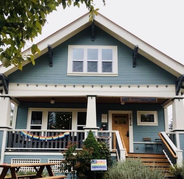 A two-story building with a porch, a signboard, and a staircase leading to the entrance. - The Alberta Petite Hotel (Portland)