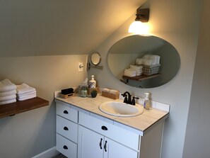 A bathroom with a white sink, black faucets, a mirror, and a towel rack. - The Alberta Petite Hotel (Portland)
