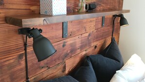 A wooden headboard with a shelf holding a tissue box, a vase with a sunflower, and a lamp. - The Alberta Petite Hotel (Portland)