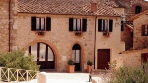 A stone building with a tiled roof, arched doorways, and windows with shutters.