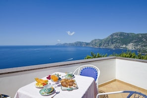 A table set with breakfast items and a view of the sea.