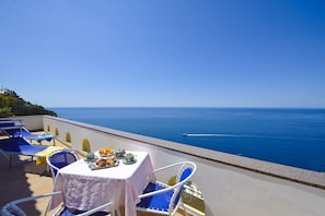 Una terraza con mesa dispuesta para el desayuno con vista al mar.