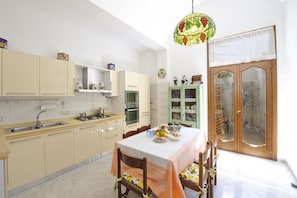 Une cuisine avec une table à manger pour quatre personnes, un lustre et une porte en bois dotée de panneaux de verre.