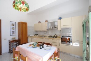 A compact kitchen with a dining table set for four, a microwave, oven, and a hanging light fixture.
