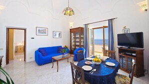 Ein Wohnzimmer mit Essbereich, einem Fernseher und Meerblick.