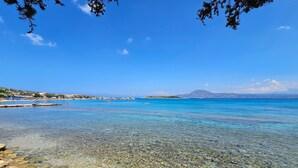 On voit clairement une plage avec un rivage rocheux et des bateaux sur l’eau.