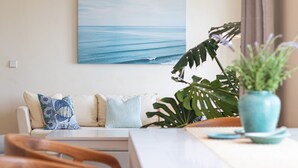 Un salon avec un canapé, une table basse et un tableau représentant l’océan.