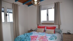 Ein Schlafzimmer mit Bett, Nachttischen, einem Fenster und Vorhängen.