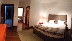 Habitación de hotel con una cama grande, una mesita de noche, una lámpara, un cuadro en la pared y piso de madera.