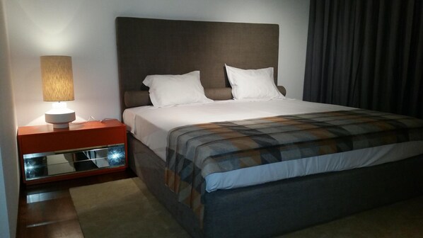 Une chambre d’hôtel avec un lit, une table de chevet avec une lampe et un miroir.