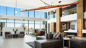 A spacious lobby with a modern design, featuring a large seating area, a reception desk, and large windows offering views of the city.
