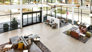A spacious lobby with modern seating, large windows, and a view of the street. - Ayres Hotel San Diego South - Chula Vista (Chula Vista)