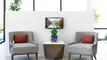 Una habitación moderna con dos sillones grises, una mesita de madera y un cuadro enmarcado en la pared.