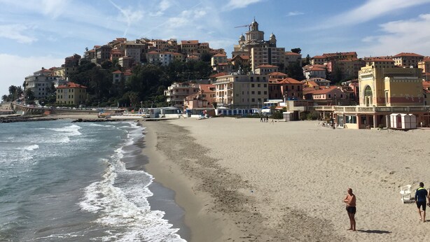 A beach with buildings in the background, a clear sky, and a few people and a dog on the sand. - Idyllically situated, comfortable detached country house in a stylish ambience (Dolcedo)