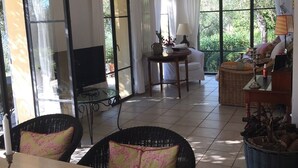 A spacious living area with a large window, a television, and a dining table with a vase of flowers. - Idyllically situated, comfortable detached country house in a stylish ambience (Dolcedo)