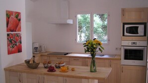 Une cuisine avec des meubles en bois, un îlot central orné d’un vase de fleurs, un four à micro-ondes et un four traditionnel.