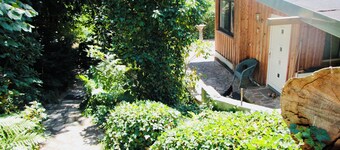 Modernly furnished bungalow with fireplace, surrounded by greenery.