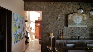 A dining area with a stone wall, wooden ceiling, and a table with chairs. - Vista paradisiaca (Angra dos Reis)