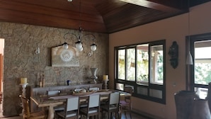 A dining area with a stone wall, wooden ceiling, and a large window. - Vista paradisiaca (Angra dos Reis)