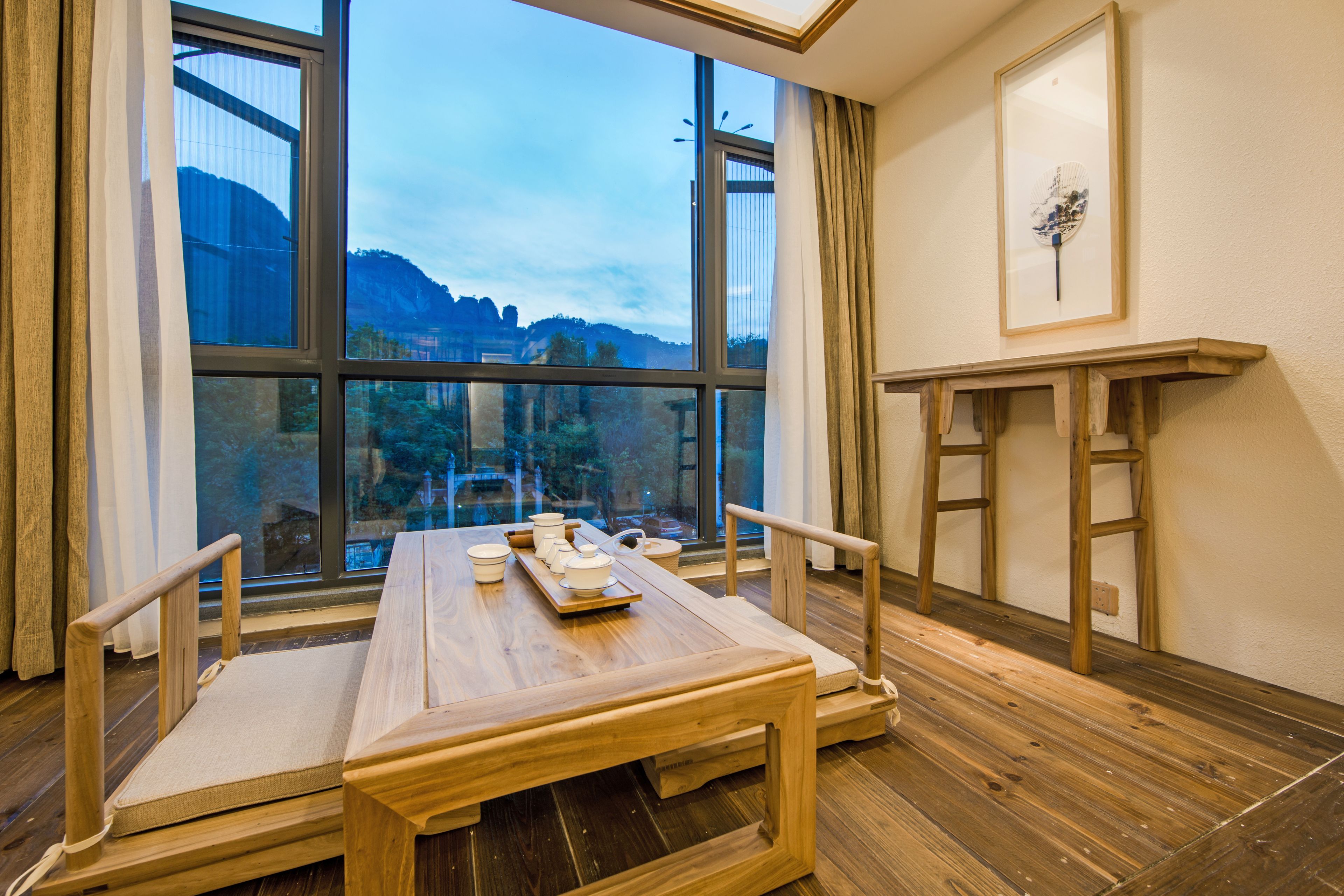 A room with a wooden table set for tea, large windows with a view of mountains, and a wooden ladder against the wall.