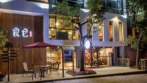 Un edificio moderno con fachada de madera y un restaurante con terraza.
