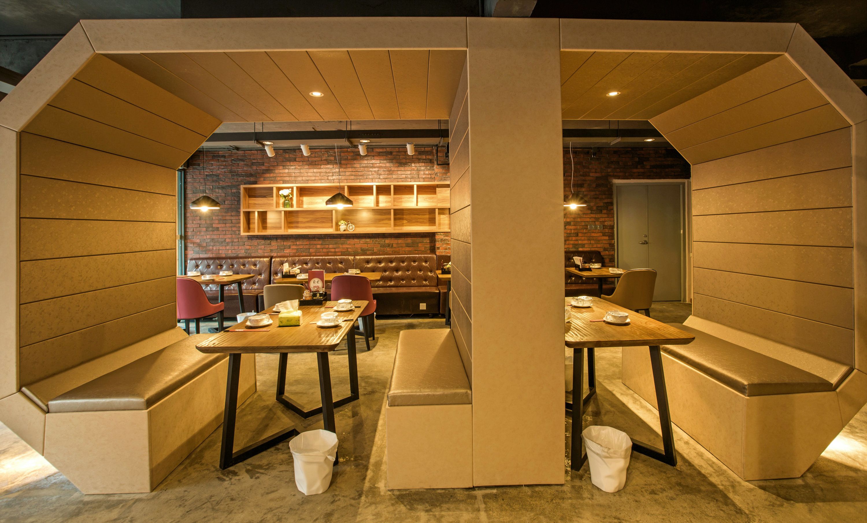 A cozy restaurant with booths and tables, brick walls, and wooden shelves.