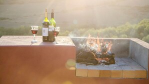 A rooftop terrace with two wine bottles and glasses, and a wood fire burning. - Bushmanspad Estate (Boesmanspad)