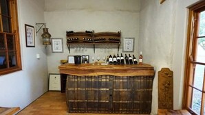 A rustic bar area with wooden shelves holding bottles and glasses, a wooden counter, and a vintage lantern. - Bushmanspad Estate (Boesmanspad)