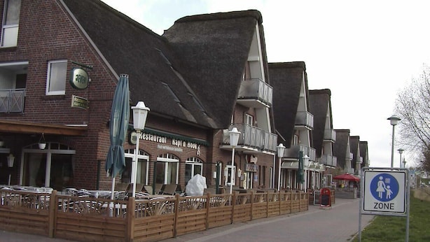 A brick building with a restaurant named "Kapi d'Hook" and a pedestrian zone sign. - Vacation home that offers rest and relaxation during every season (Niedersachsen)