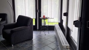 A room with a grey sofa, a small round table with a red object, and a radiator. - Vacation home that offers rest and relaxation during every season (Niedersachsen)