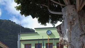 A two-story building with a green facade, wooden balconies, and a clock on the second floor. - Quiet apartment with sea views (Agulo)
